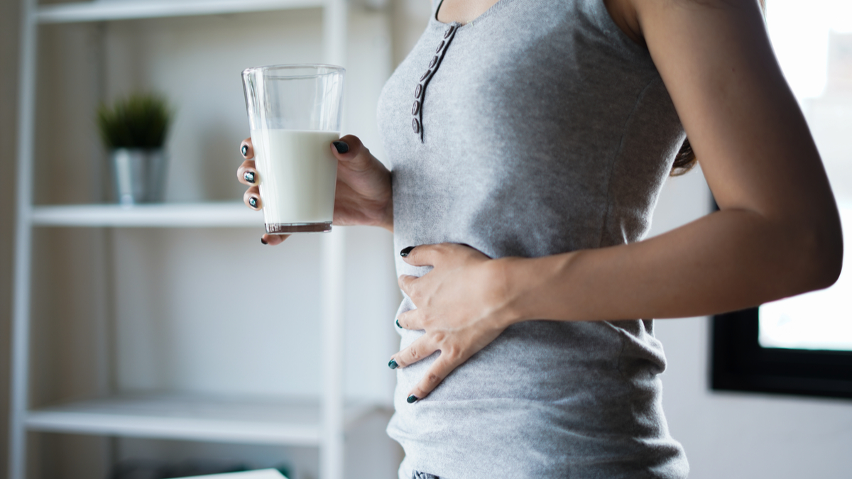 woman holding stomach and milk food intolerances