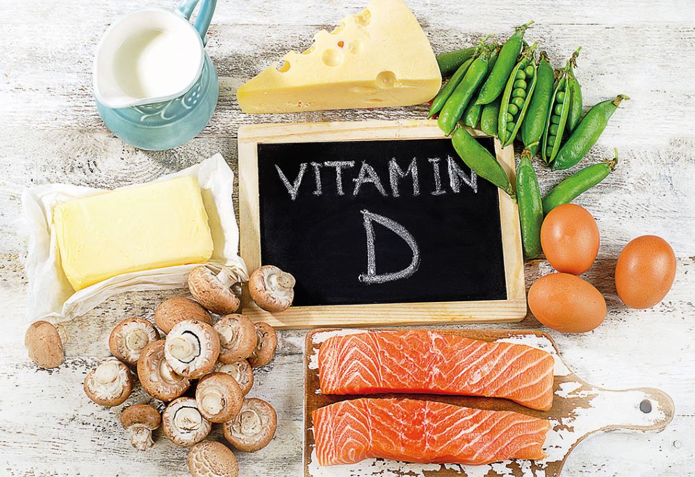 vitamin D rich foods including cheese, salmon, dairy, mushrooms on a white background with a sign