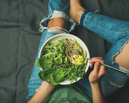 woman eating a nutritious meal with green vegetables including the best foods for brain health