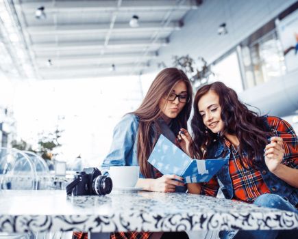 two women looking at calories on menus in a restaurant