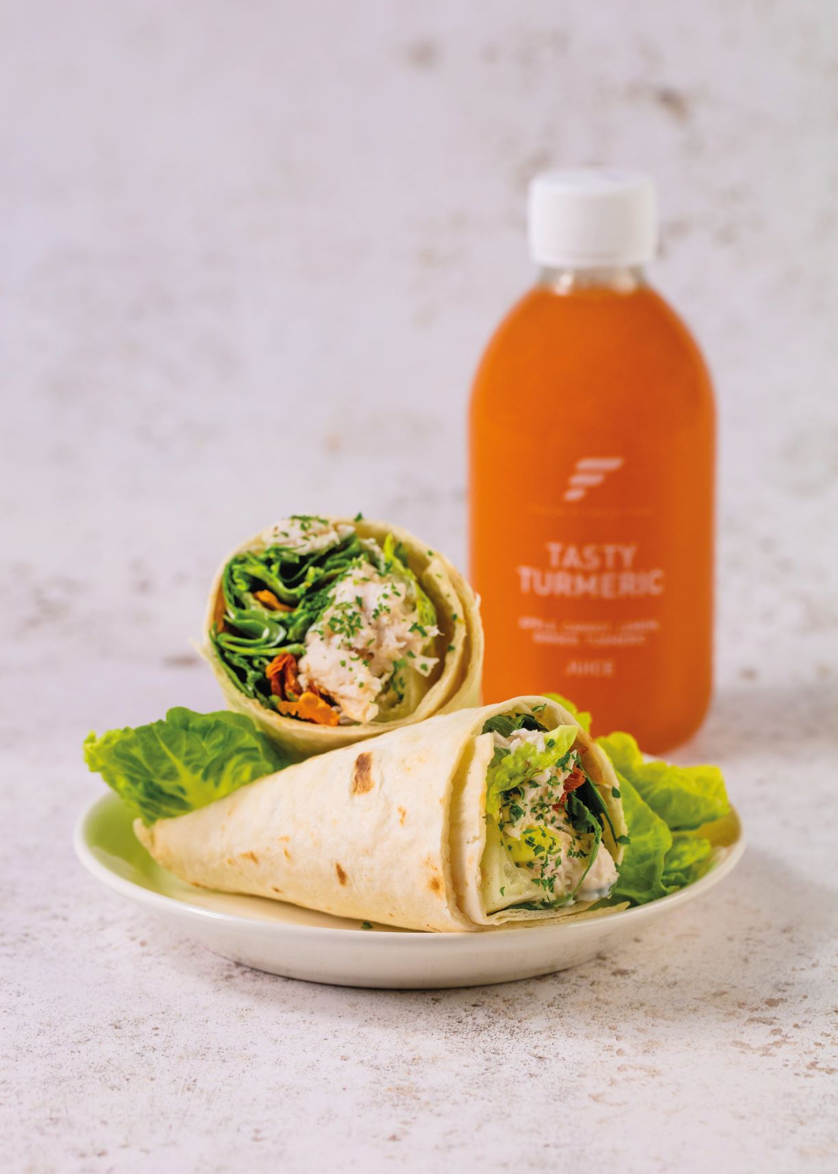 tortilla wrap with lettuce and healthy summer foods in, next to bottle with turmeric health shot, from fresh food fitness meal delivery service
