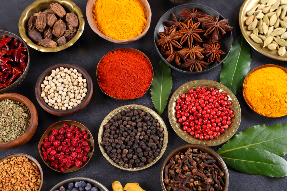 bowls of different healthy cooking spices including turmeric ginger cinnamon star anise