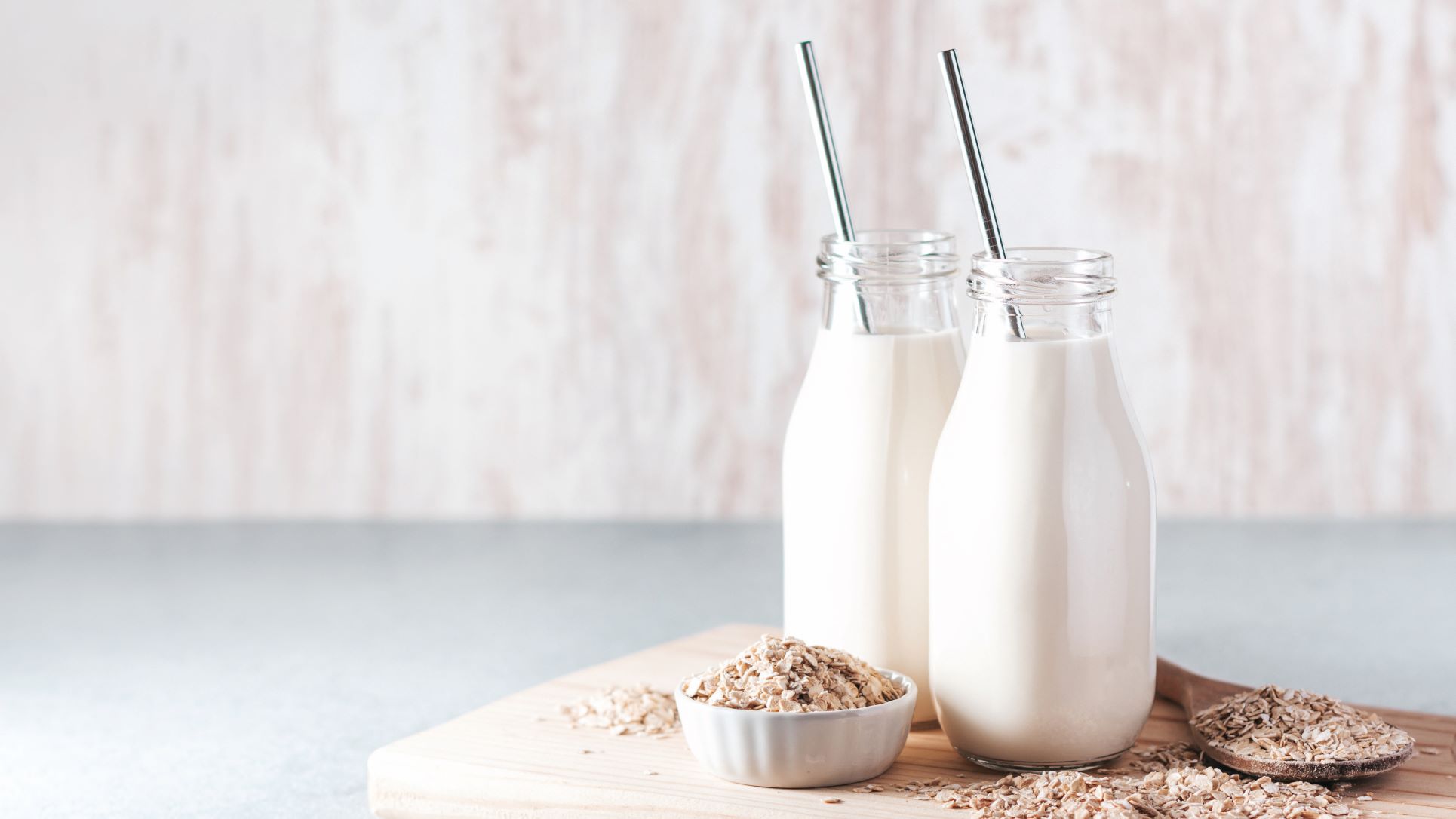 glass jars of milk or yoghurt next to whole oats on white background, showing how to avoid ultra processed foods upfs