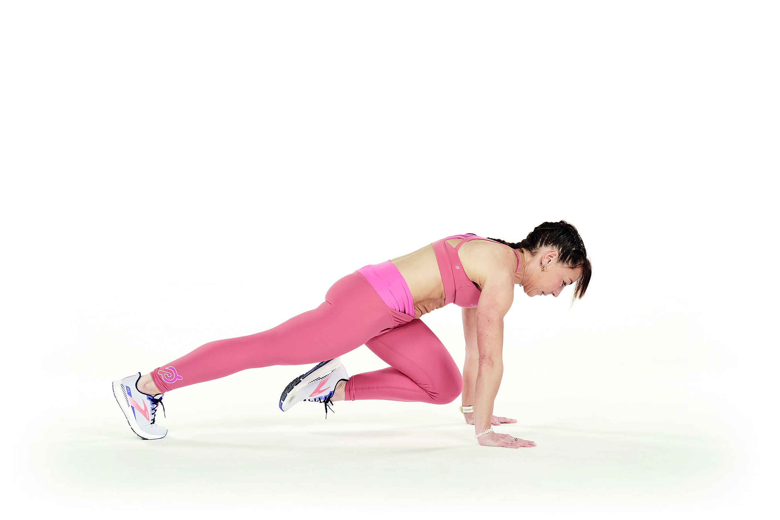 woman wearing pink activewear demonstrates how to do mountain climbers