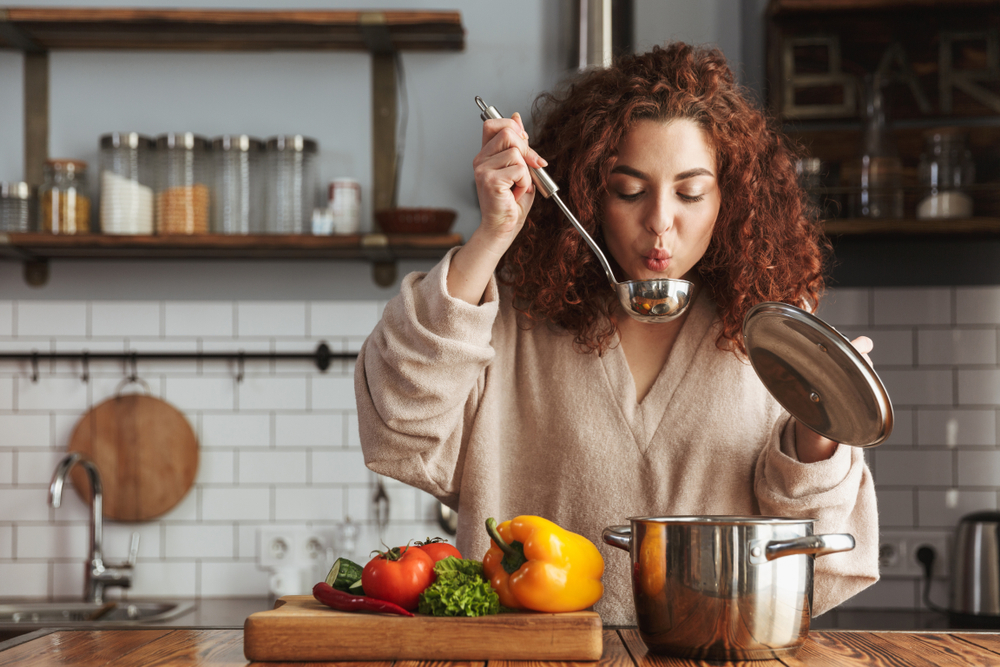 woman tasting meal cooking vegetables in the kitchen