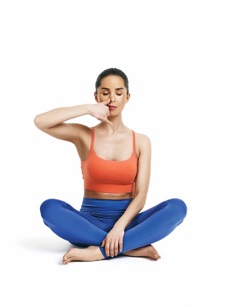 Frau, die alternative Nasenatmungstechnik im Yoga demonstriert