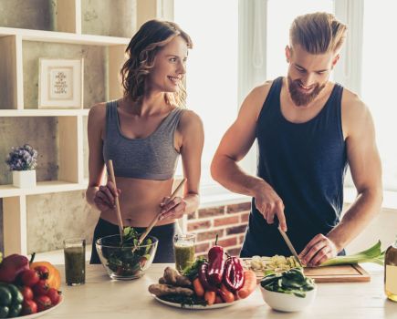 fit man and woman preparing healthy meal together