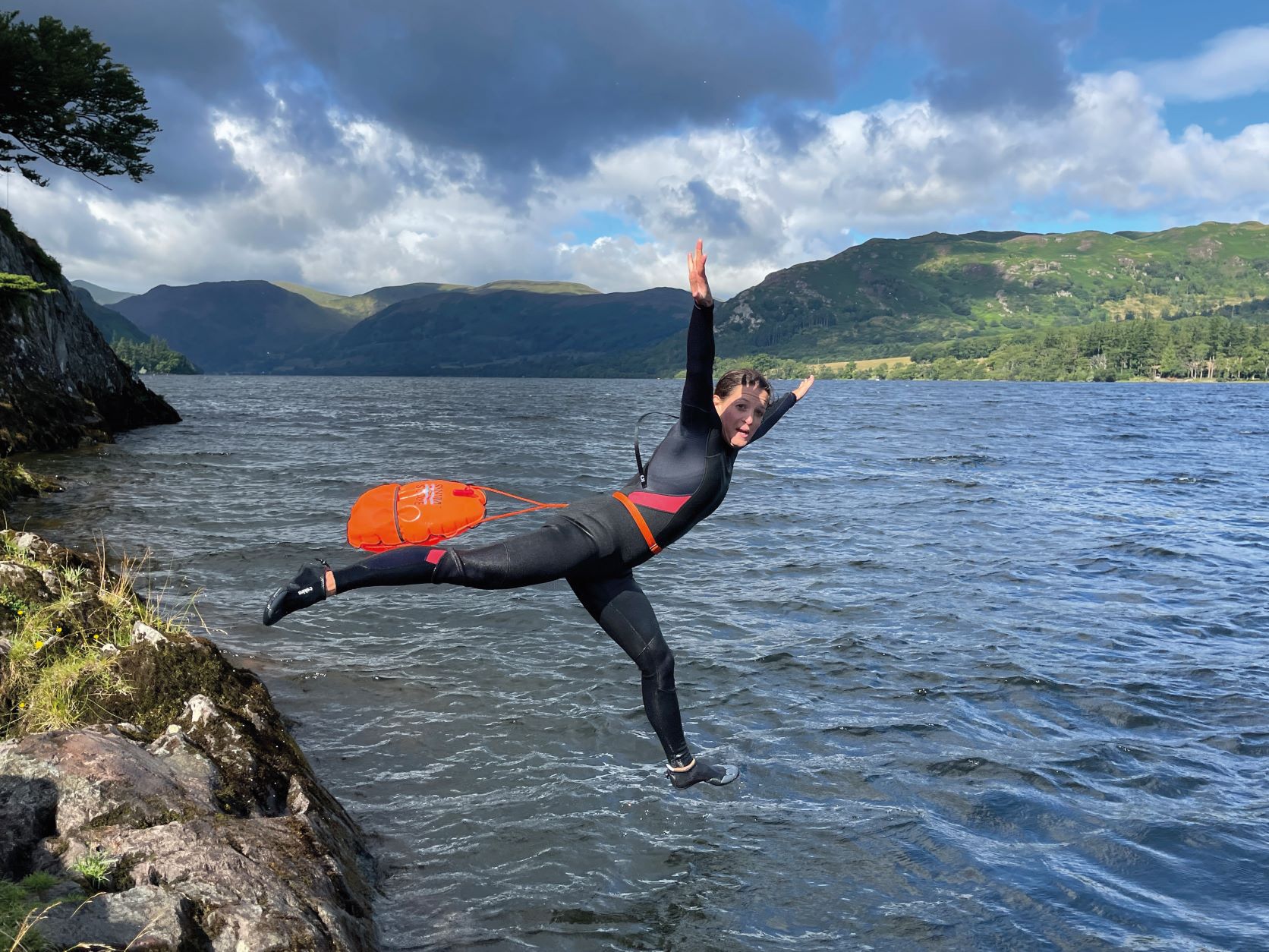 woman jumping off ledge to go wild swimming in the lake district