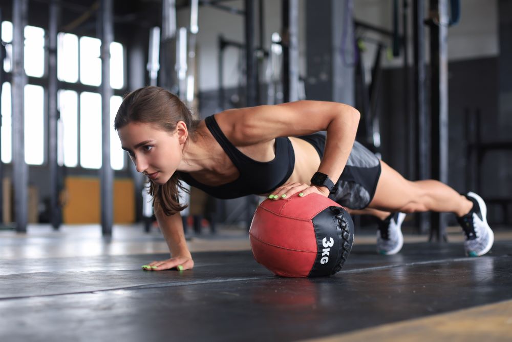 woman demonstrates medicine ball push up