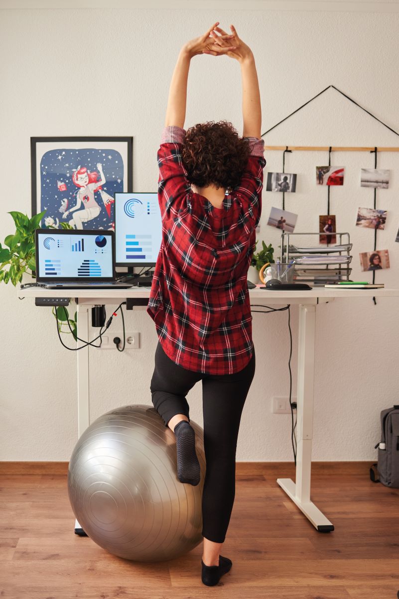 woman standing at desk stretching above head