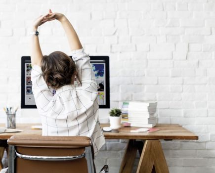 woman sitting at desk stretching