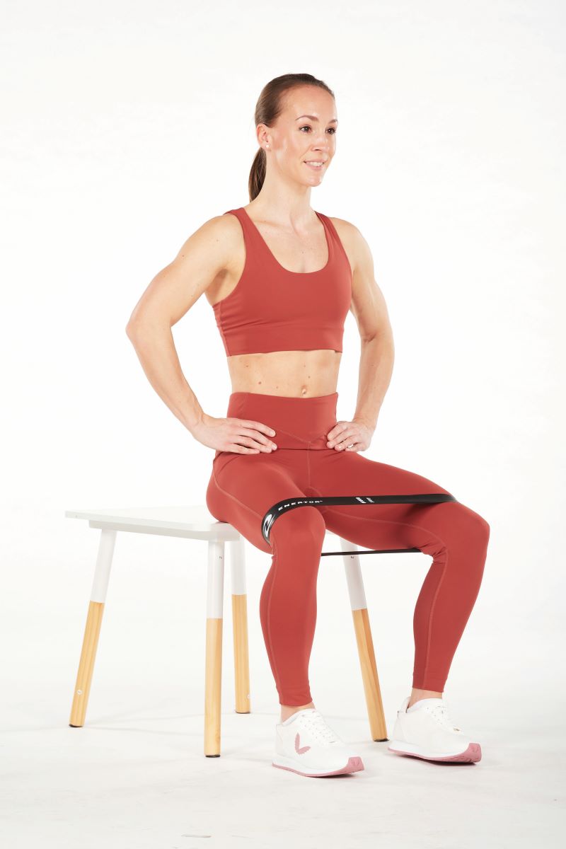 woman demonstrates seated clams in resistance band workout for runners