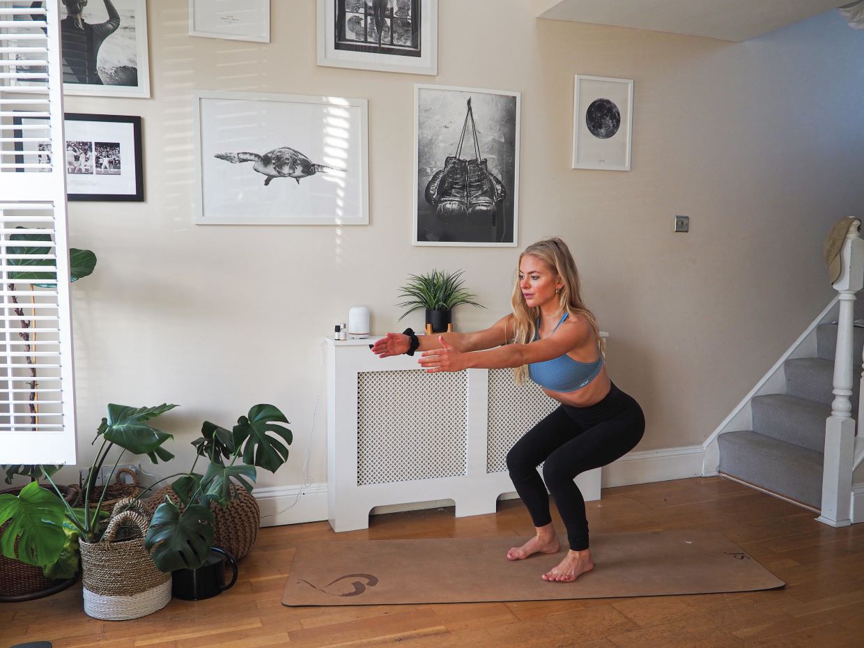 woman demonstrating squat in 10 minute home workout for busy schedules