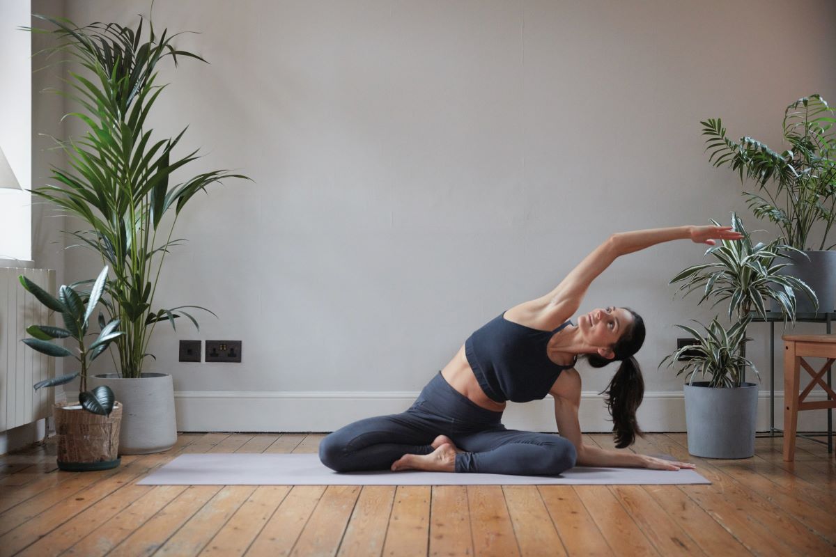 woman demonstrating yoga side stretch at home