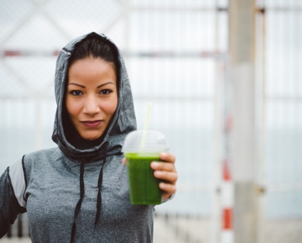 fitness woman on run drinking green smoothie
