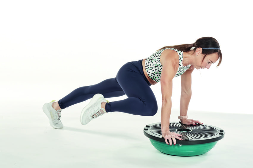 woman performs spiderman crunch on bosu ball