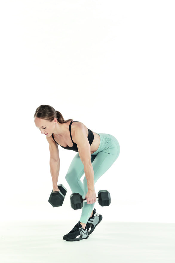 woman uses a pair of dumbbells in single leg deadlift