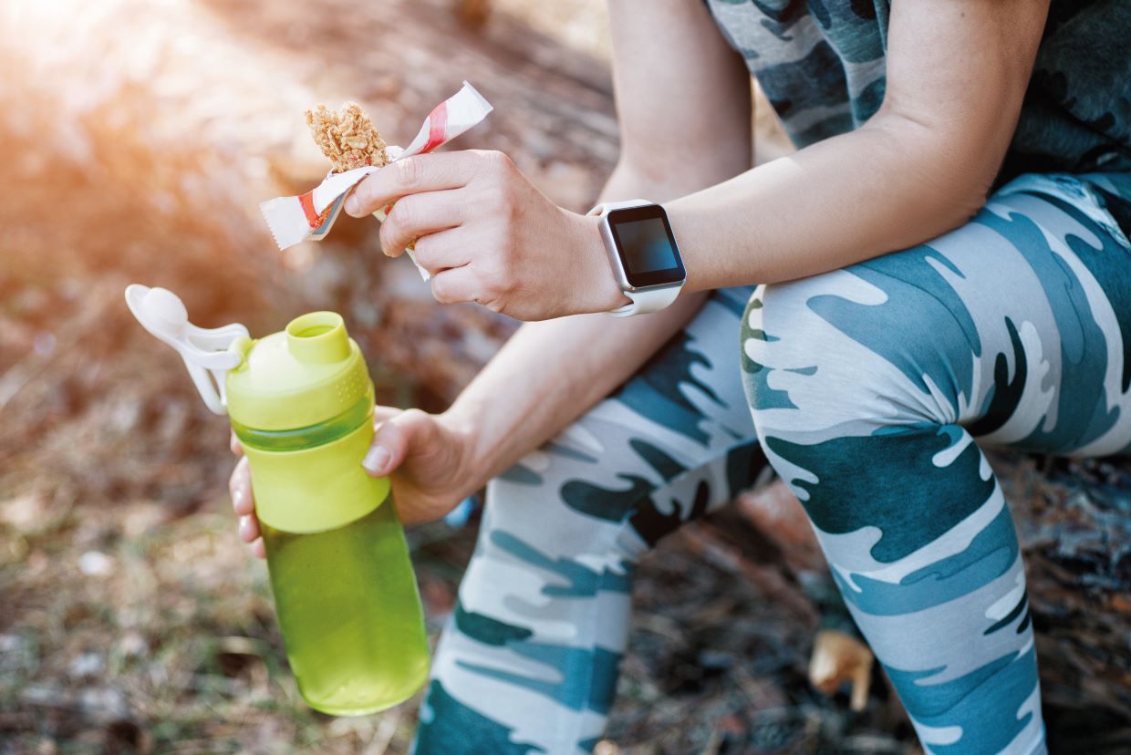 woman eats protein bar snack during a run nutrition tips for runners