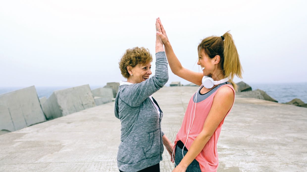 two women high five after running together; one woman is young, the other is mature
