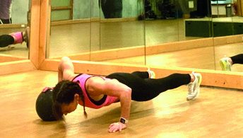 woman demonstrates Split Push-up Knee Tuck