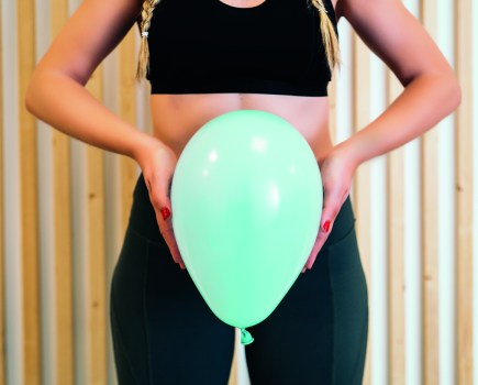 woman holding balloon over abdomen, pelvic floor training concept