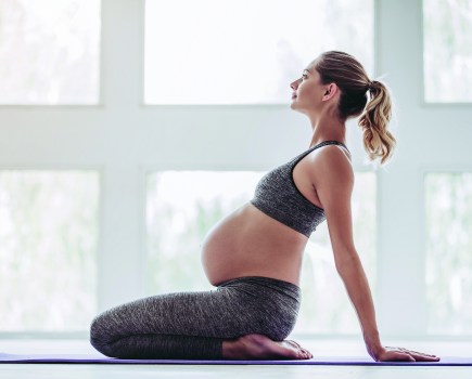 prenatal yoga woman in pregnancy stretching on mat