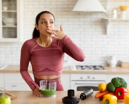 woman making smoothie licking fingers