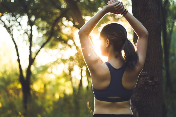 woman doing workout standing in a wooded area or orest