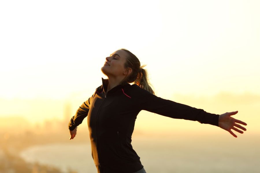 woman stretching arms on run, feeling mindful and happy