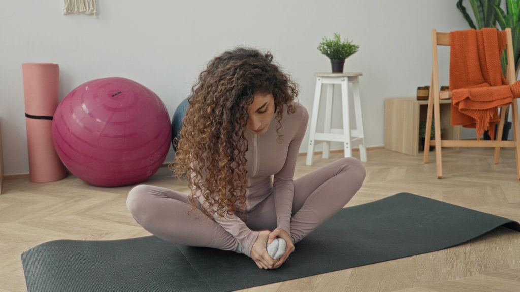 woman in butterfly pose holding feet and circling her torso