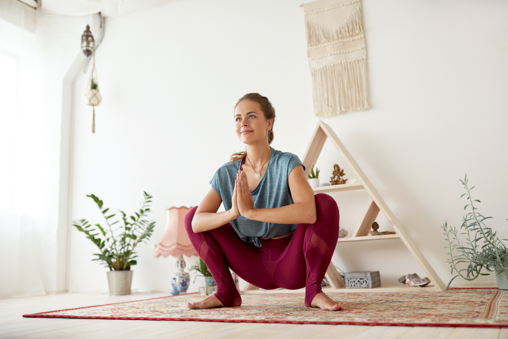 woman holding malasana, garland pose, a deep squat position with her hands joined in namaskar mudra