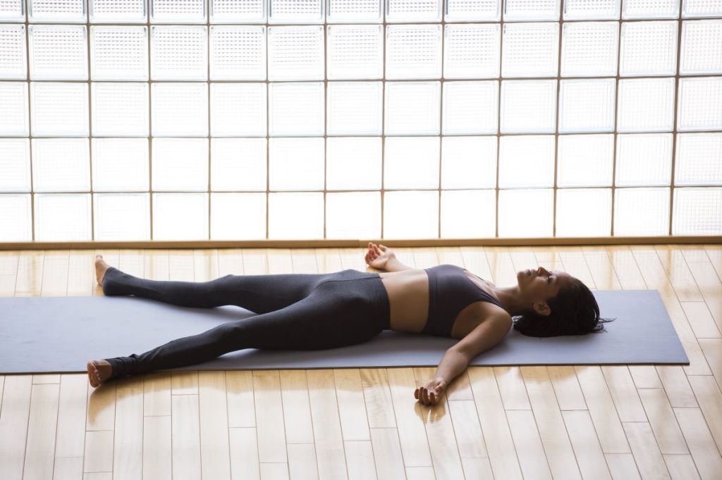 woman in shavasana, corpse pose, relaxing with eyes closed