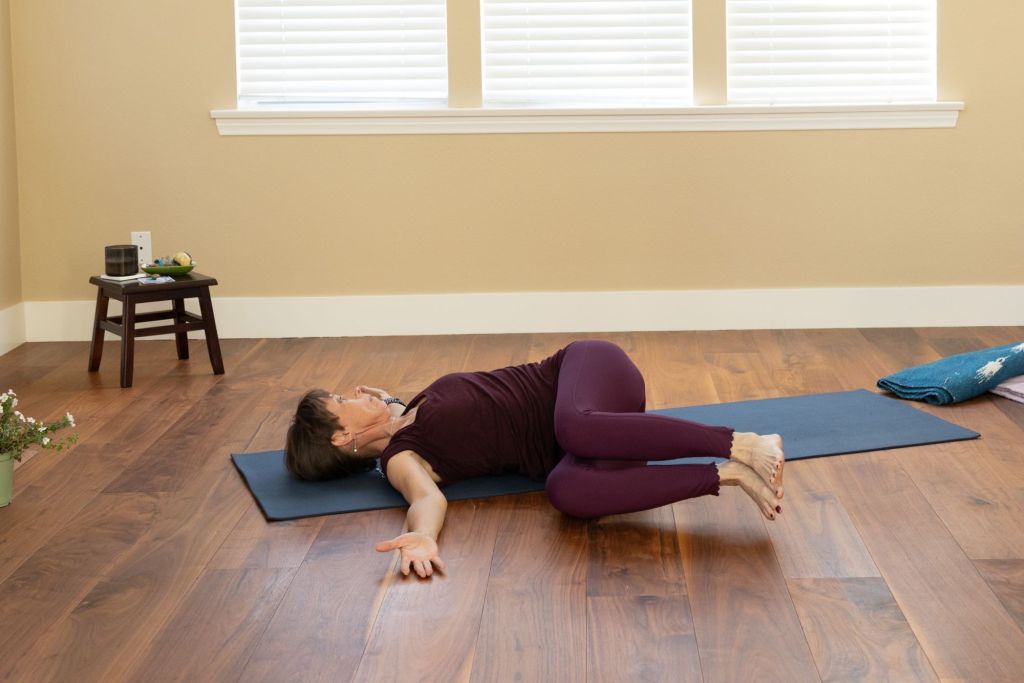woman lying on back with knees to the side, supine spinal twist