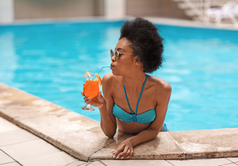 woman sipping summer cocktail by the pool