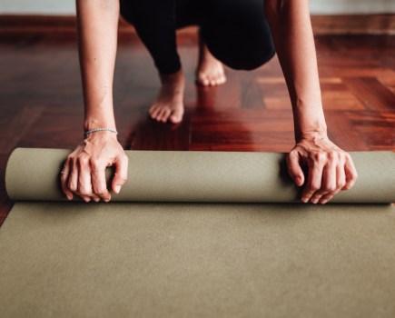 yoga teacher rolling out yoga mat for practice