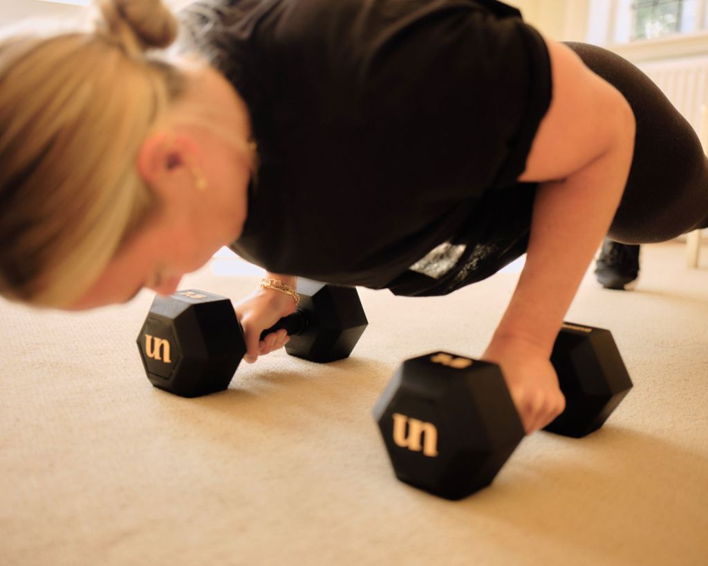 woman using unbound dumbbells during a plank exercise