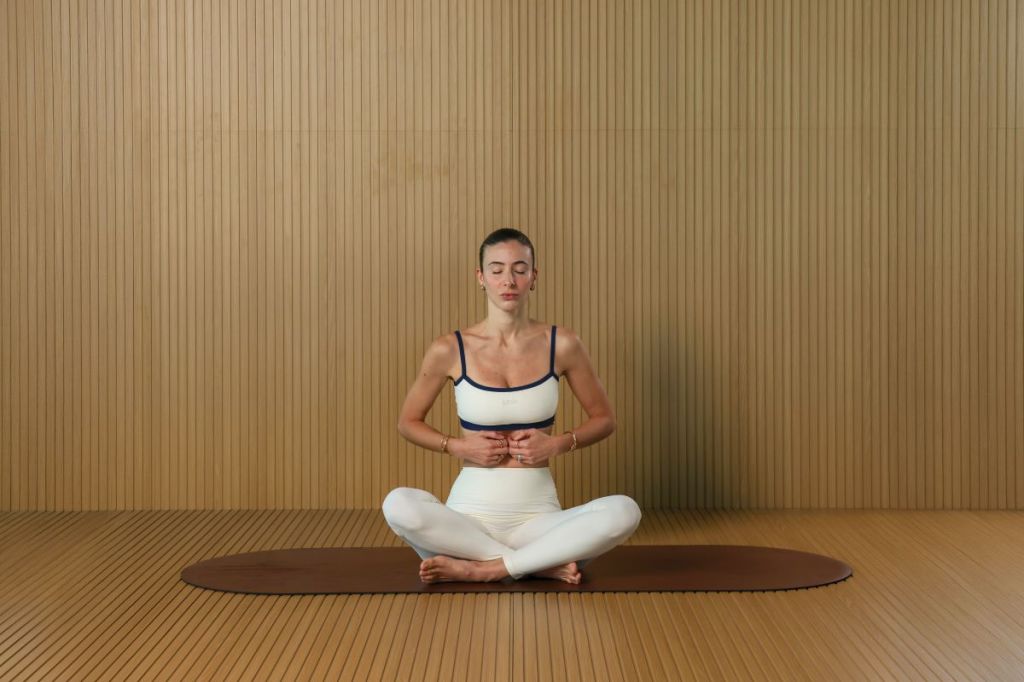 woman doing Lymphatic tapping warm-up deep breathing with hands on belly