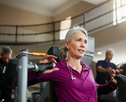 midlife woman strength training using resistance machine in the gym, she adapts workouts for menopause and beyond