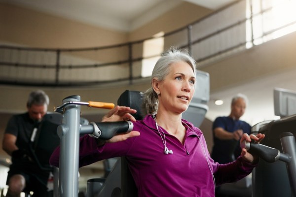 midlife woman strength training using resistance machine in the gym, she adapts workouts for menopause and beyond