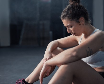 woman feeling tired during gym workout, sitting on the floor resting