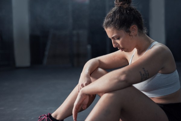 woman feeling tired during gym workout, sitting on the floor resting