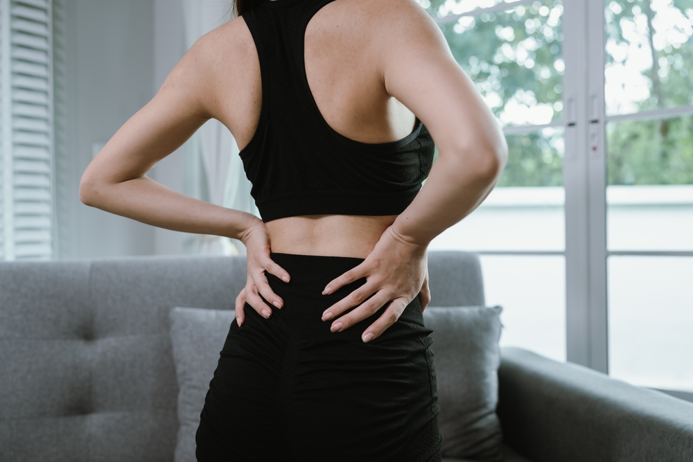 woman wearing activewear with lower back pain before training at the gym