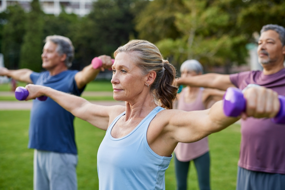 midlife mature woman strength training outside in a workout class
