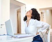 woman with back pain sitting at her desk working