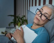 Mature woman that has fallen asleep with her glasses on and a book on her chest.