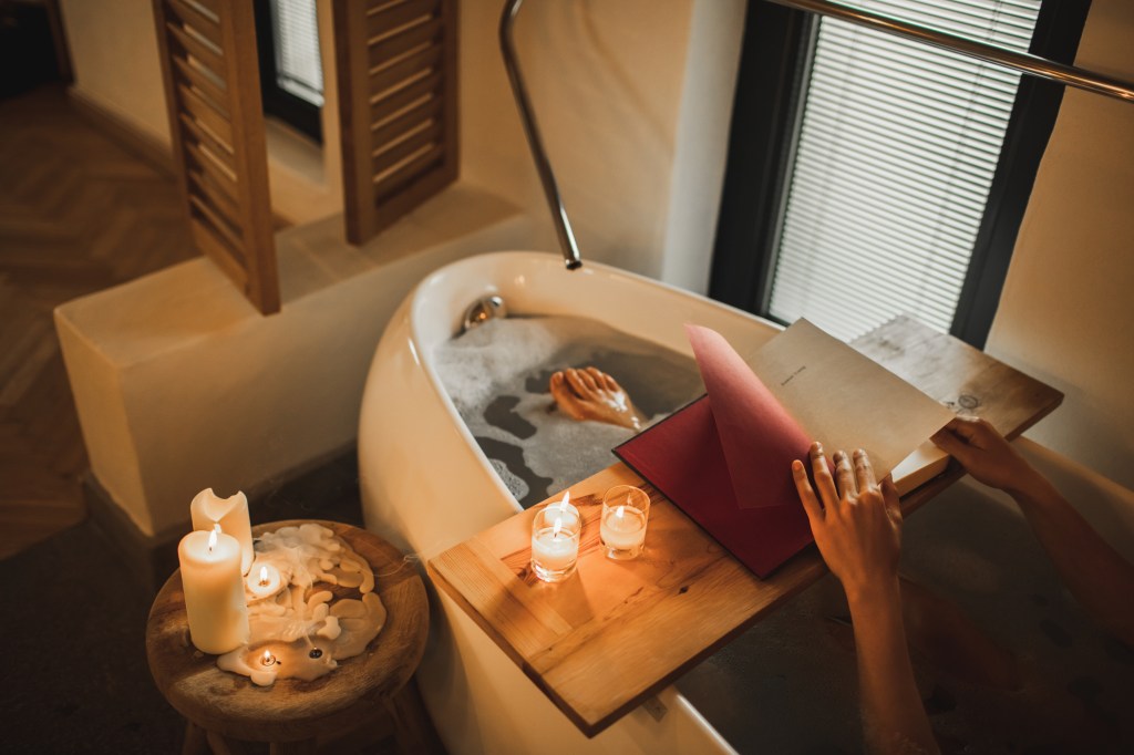 Resting in bathroom, calmness and mental health. Time to self and quiet. Female hands holding book. Overhead view and copy space background with unrecognizable person.