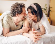 Happy couple lying down in bed. They enjoy in love,embracing, kissing, laughing. Concept of love.