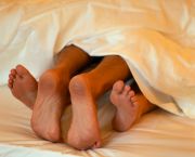 The toes of a woman and man in bed together