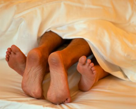 The toes of a woman and man in bed together