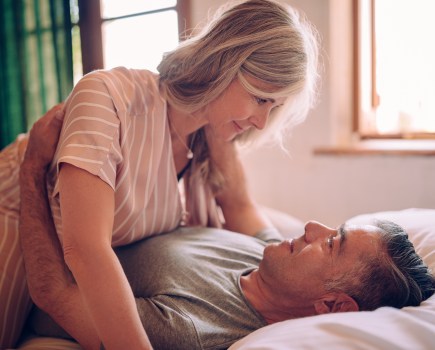Mature husband and wife flirting while lying down in bed